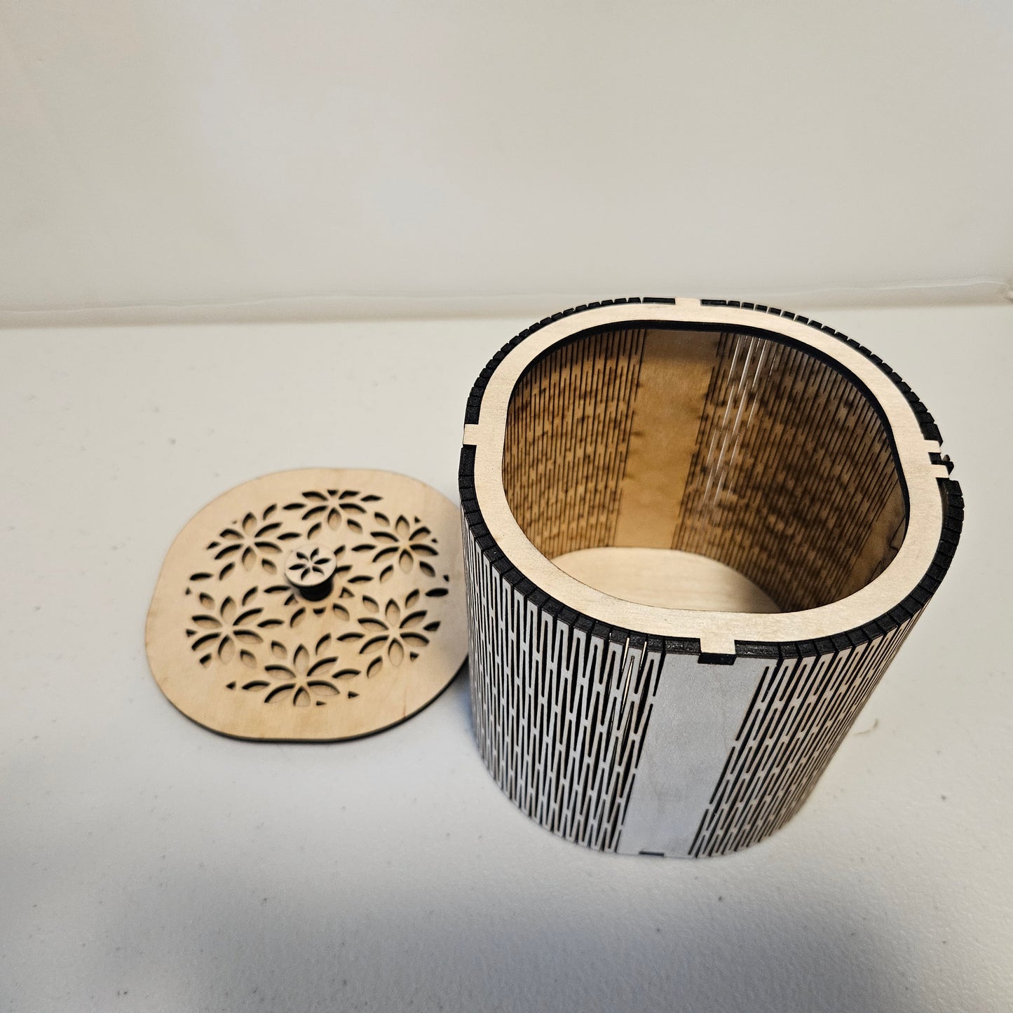 Rounded square wooden box with a flower pattern design cut out of the top