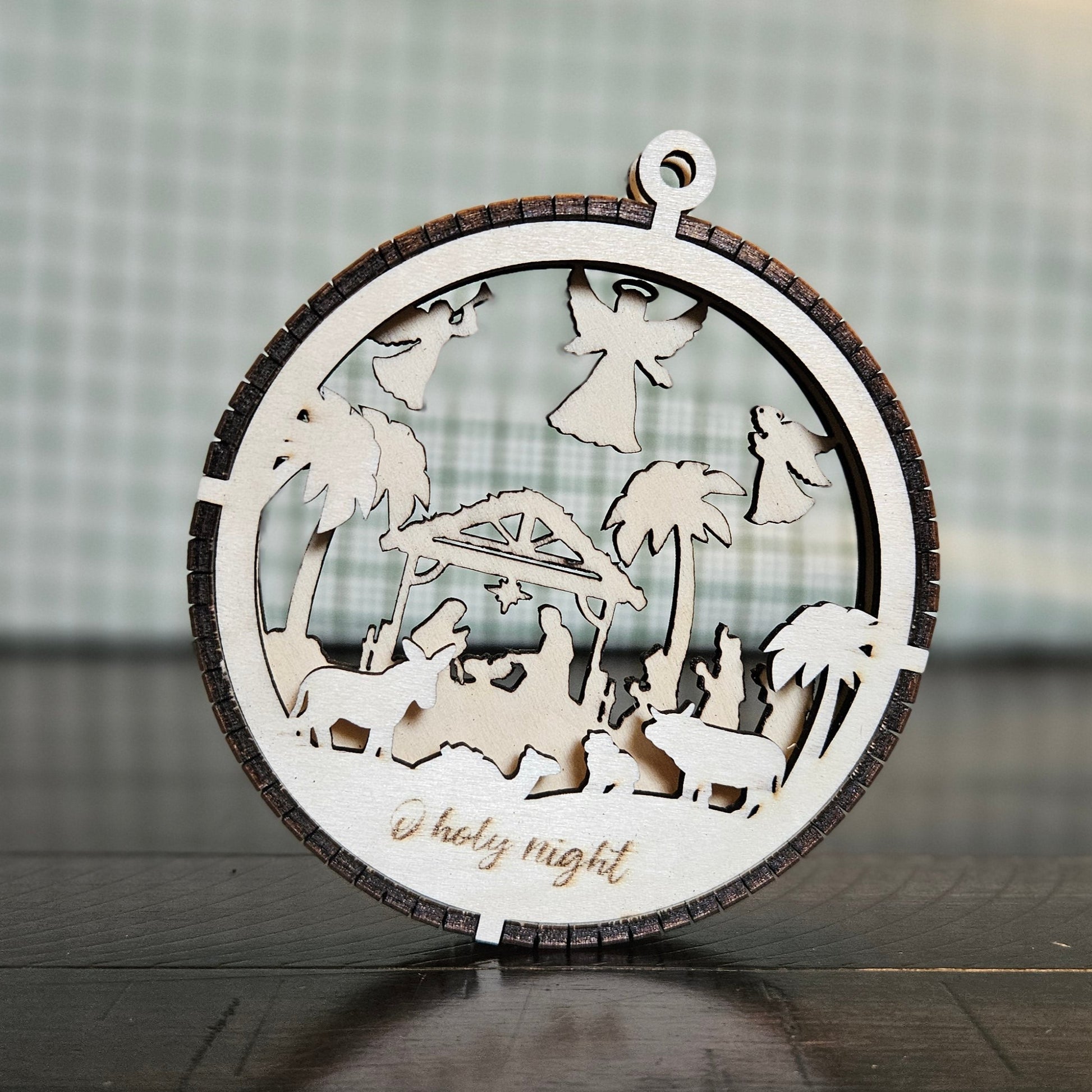 2-Layer wooden ornament with the words "O holy night" under barn animals in the foreground and the nativity in the background