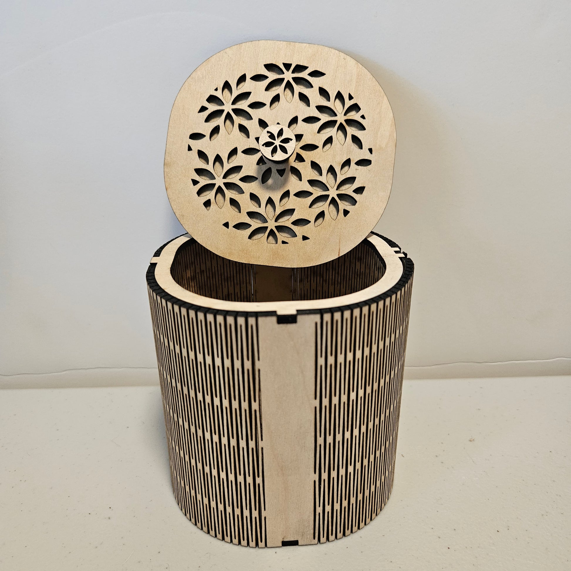 Rounded square wooden box with a flower pattern design cut out of the top