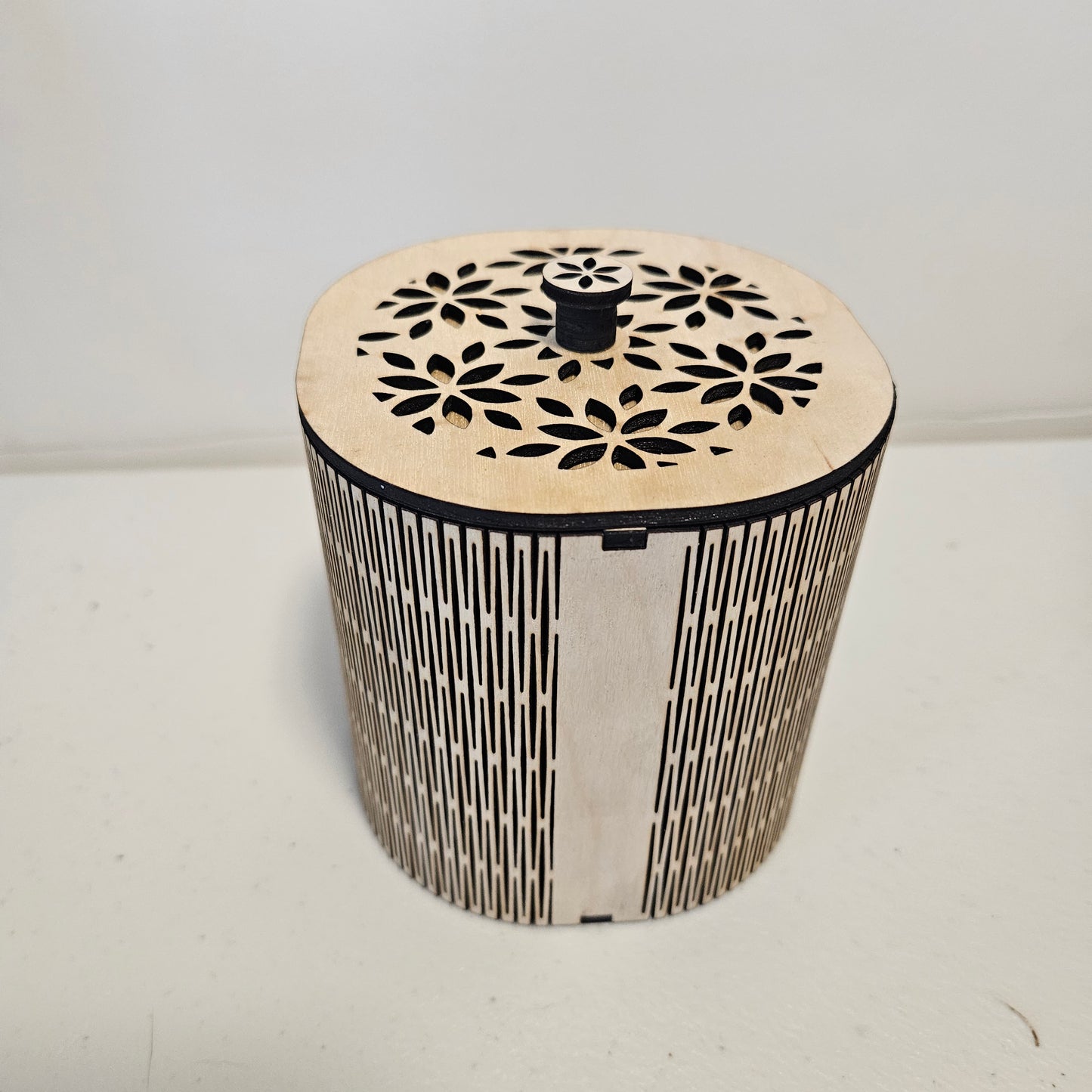 Rounded square wooden box with a flower pattern design cut out of the top